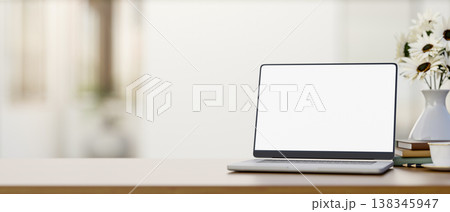 White screen laptop with coffee and books aside flower vase on wooden counter table in a bright room White screen laptop with coffee and books aside flower vase on wooden counter table in a bright room 138345947