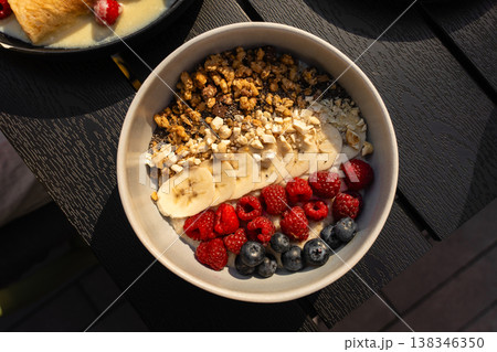Healthy breakfast bowl with granola, banana and fresh berries in natural light Healthy breakfast bowl with granola, banana and fresh berries in natural light 138346350