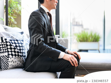 ソファに座るスーツ姿の男性の側面 ソファに座るスーツ姿の男性の側面 138346557