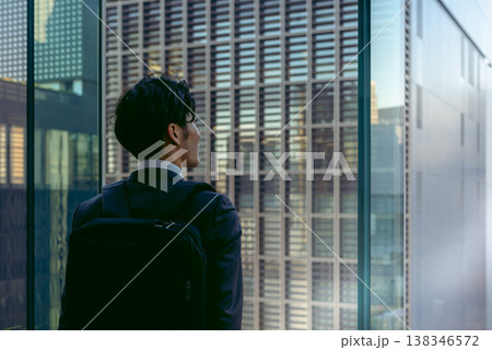 高層ビルから街並みを見つめる男性 138346572