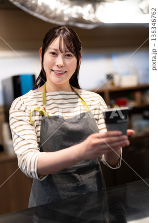 カウンター越しにテイクアウトコーヒーを渡す笑顔のカフェ店員 138346762