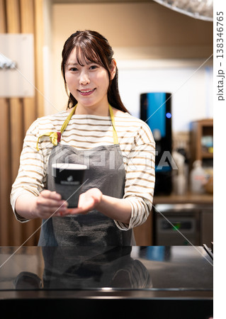 カウンター越しにテイクアウトコーヒーを渡す笑顔のカフェ店員 138346765