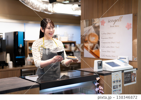 コーヒーとドーナツを提供する笑顔のカフェ店員 138346872