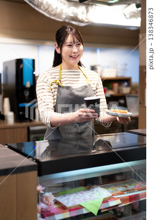 コーヒーとドーナツを提供する笑顔のカフェ店員 コーヒーとドーナツを提供する笑顔のカフェ店員 138346873
