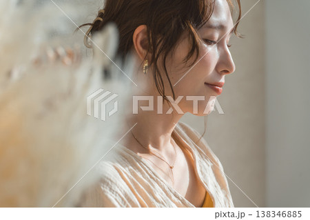 西陽の当たるリビングにいる女性とドライフラワー（モデル,ファッション,光,影） 138346885