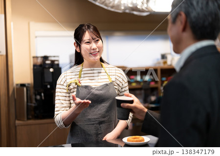 笑顔で接客をして注文の品を渡すカフェの女性店員 138347179