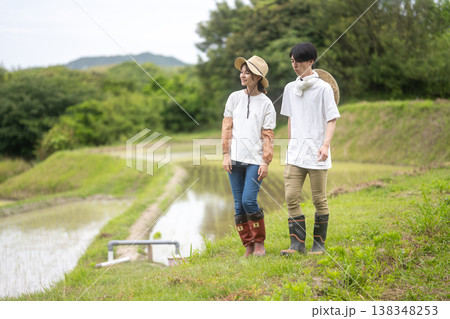 田んぼの横を歩く若い男女の農家 138348253
