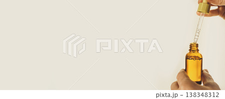 Hand holding and preparing an essential oil dropper bottle, banner format Hand holding and preparing an essential oil dropper bottle, banner format 138348312