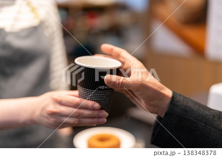 カフェでテイクアウト用のコーヒーを手渡す女性店員 138348378