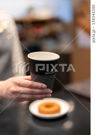 カフェでテイクアウト用のコーヒーを手渡す女性店員 カフェでテイクアウト用のコーヒーを手渡す女性店員 138348380