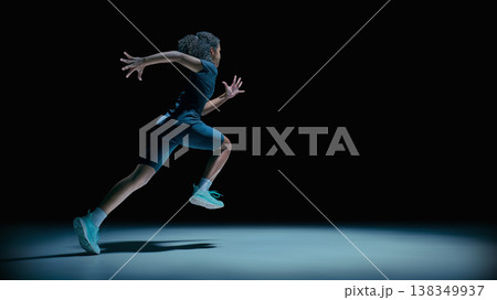 Female teenager athlete jumping in motion wearing futuristic visor in dark studio. Female teenager athlete jumping in motion wearing futuristic visor in dark studio. 138349937