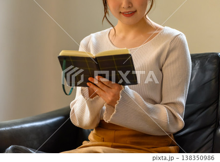 ソファでノートを開いて見ている女性 ソファでノートを開いて見ている女性 138350986