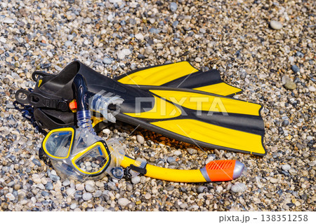 Flippers and snorkeling tube on sea shore 138351258