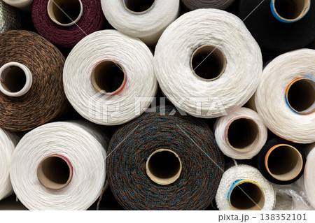 Industrial textile thread spools stacked warehouse fiber production materials visible texture, twist pattern detail. Circular rolls manufacturing process, material quality, order and consistency. Industrial textile thread spools stacked warehouse fiber production materials visible texture, twist pattern detail. Circular rolls manufacturing process, material quality, order and consistency. 138352101