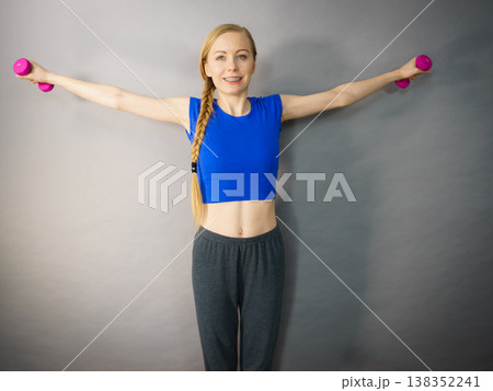 Teenage woman working out at home with dumbbell Teenage woman working out at home with dumbbell 138352241