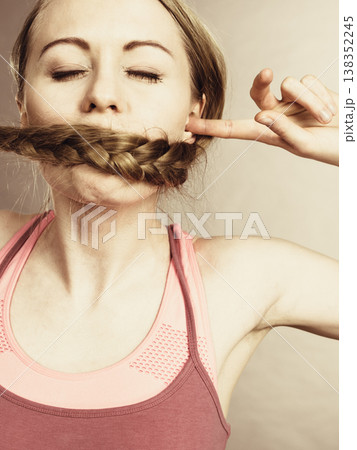 Woman covering her mouth with blonde braid Woman covering her mouth with blonde braid 138352245
