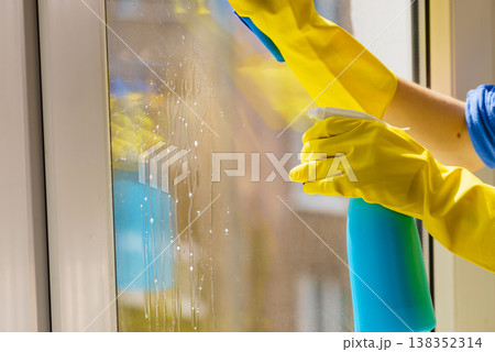 Gloved hand cleaning window rag and spray Gloved hand cleaning window rag and spray 138352314