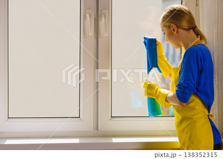 Woman cleaning window at home Woman cleaning window at home 138352315
