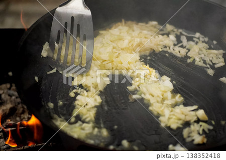 Roasting onions in pan with oil on fire. 138352418