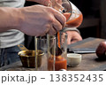 Pouring tomato juice into glasses through spoon. 138352435