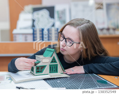 Caucasian young woman making a model of a building. Student of the construction university. Caucasian young woman making a model of a building. Student of the construction university. 138352549
