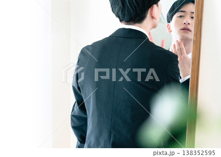 鏡の前で身だしなみを整えるスーツ姿の男性 鏡の前で身だしなみを整えるスーツ姿の男性 138352595