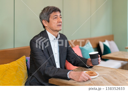 カフェでコーヒーとドーナツを手に笑顔で休憩するシニアビジネスマン カフェでコーヒーとドーナツを手に笑顔で休憩するシニアビジネスマン 138352633
