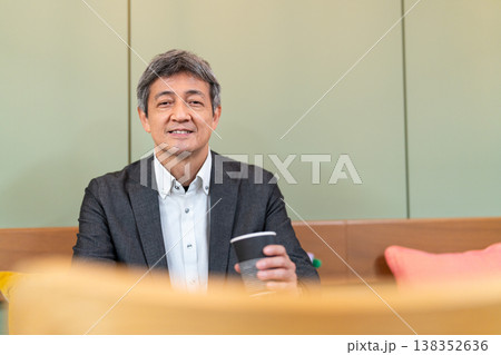 カフェでコーヒーを飲みながらリラックスするシニアビジネスマン 138352636