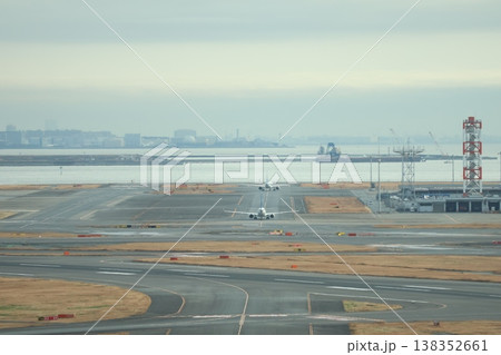 2機の飛行機が滑走路を走る空港と海と船と海岸の街並みと霞む空の風景 2機の飛行機が滑走路を走る空港と海と船と海岸の街並みと霞む空の風景 138352661
