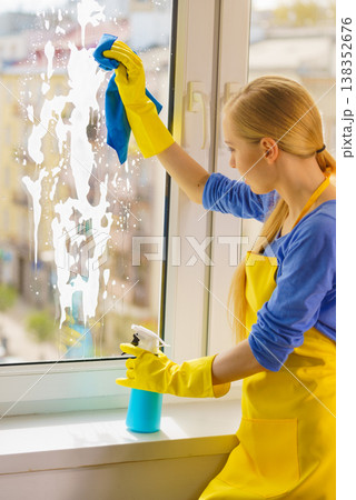 Woman cleaning window at home 138352676