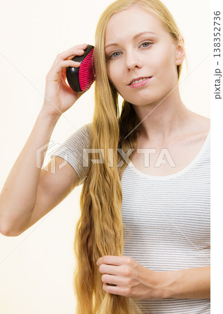 Blonde girl brushing her long hair Blonde girl brushing her long hair 138352736