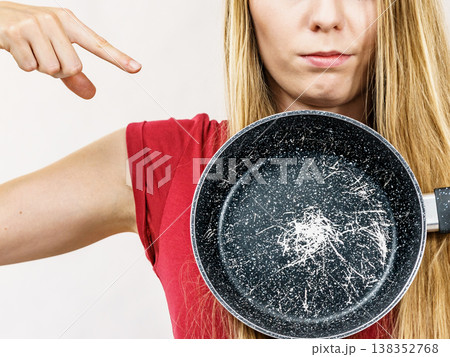 Girl holding scratched frying pan Girl holding scratched frying pan 138352768