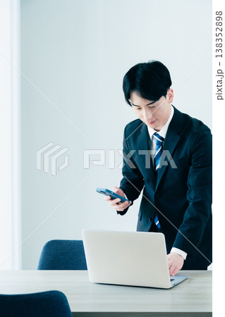 オフィスで電話する若いビジネスマン オフィスで電話する若いビジネスマン 138352898