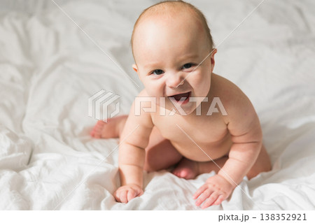 Funny happy newborn baby on a white bed at home, the concept of a happy healthy infant baby. Generation alpha and gen alpha 138352921