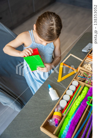 Little girl choosing colorful felt sheets for craft project at table with creative supplies. Kids creativity development fine motor skills and learning through play concept. Little girl choosing colorful felt sheets for craft project at table with creative supplies. Kids creativity development fine motor skills and learning through play concept. 138353052