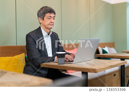 カフェでパソコン作業をするシニアのビジネスマン カフェでパソコン作業をするシニアのビジネスマン 138353306