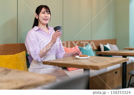カフェでコーヒーを飲みながら休憩する若い女性 カフェでコーヒーを飲みながら休憩する若い女性 138353324