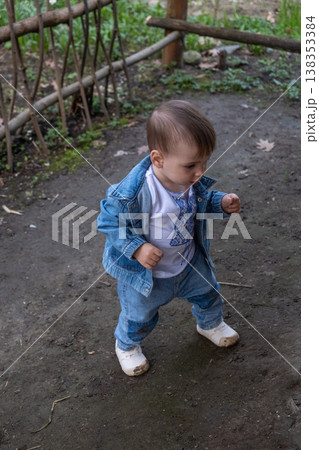 Toddler taking first steps outdoors near rustic wooden fence Toddler taking first steps outdoors near rustic wooden fence 138353384