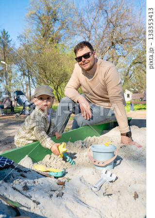 Father and son playing in sandbox outdoors on sunny day Father and son playing in sandbox outdoors on sunny day 138353413