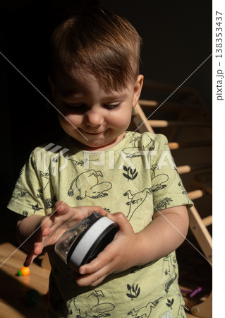 Toddler holding toy ball in warm sunlight indoors 138353437