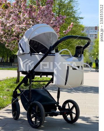 Baby stroller on park path under blooming cherry trees Baby stroller on park path under blooming cherry trees 138353522