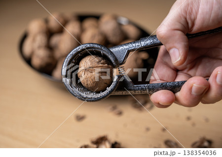 Cracking walnuts with a metal nutcracker tool Cracking walnuts with a metal nutcracker tool 138354036