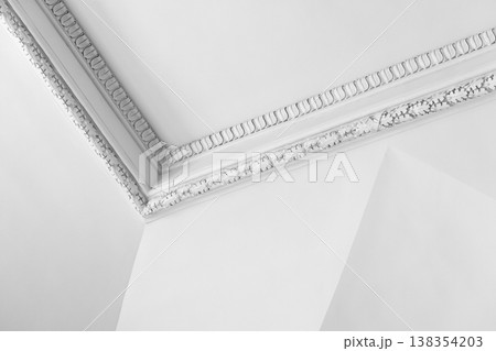 Elegant white interior showing a decorative plaster ceiling corner with ornate molding 138354203