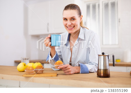 Girl dressed in man's white shirt holding cup of coffee or tea thoughtfully looking away 138355190