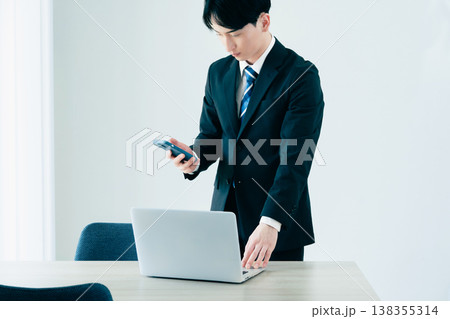 オフィスでスマホを見る若いビジネスマン オフィスでスマホを見る若いビジネスマン 138355314