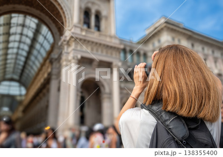 Woman traveler exploring milan, photographing the historic galleria vittorio emanuele ii with a camera, immersed in the culture and architecture of italy 138355400