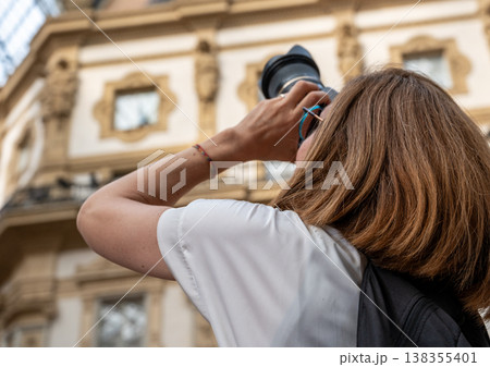 Woman capturing the intricate architecture of galleria vittorio emanuele ii in milan, engaging in tourism and exploring the historic landmark with a camera 138355401