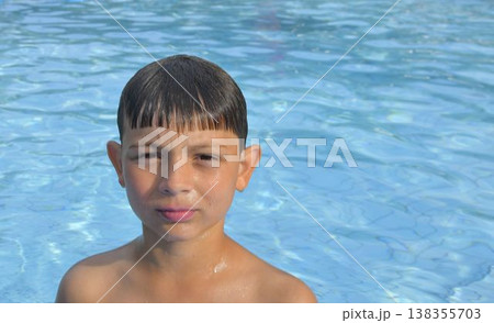 A boy in the water at a public swimming pool. A little kid at the edge of the pool. Copy space. The concept of summer, summer vacations, and leisure time. 138355703