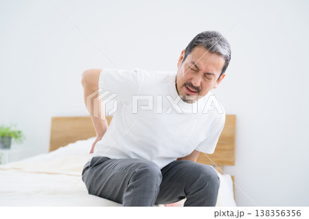 ベッドで腰の痛みに悩まされる日本人男性 ベッドで腰の痛みに悩まされる日本人男性 138356356