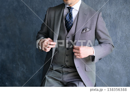 グレー背景でスーツを整える日本人男性 グレー背景でスーツを整える日本人男性 138356388